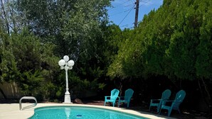 A swimming pool with a tiled edge, a small fountain, and two Adirondack chairs. - Spacious 4-bedroom house with a Pool, AC, WiFi located in Northeast Albuquerque (Albuquerque)