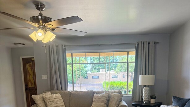 A living room with a sectional sofa, ottoman, and a ceiling fan. - Spacious 4-bedroom house with a Pool, AC, WiFi located in Northeast Albuquerque (Albuquerque)