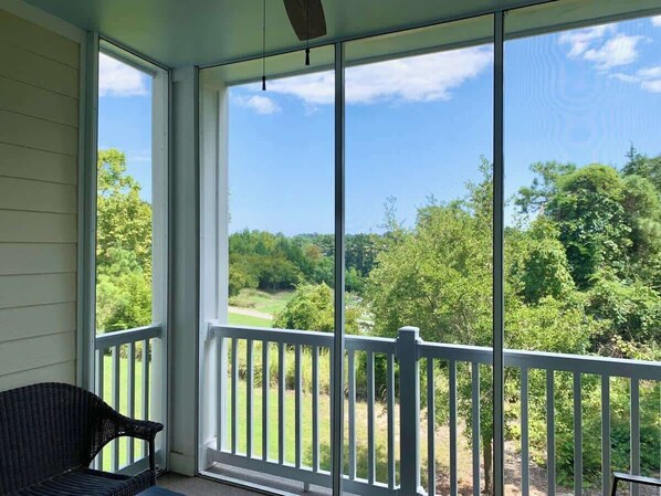 A covered porch with a view of a green landscape.