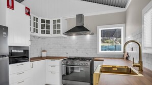 A modern kitchen with white cabinetry, a stainless steel stove, and a window with a view. - Settle Inn: Broadwater, Pet Friendly (Broadwater)