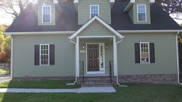 A two-story house with a front porch, a brick foundation, and a number '7425' on the door.