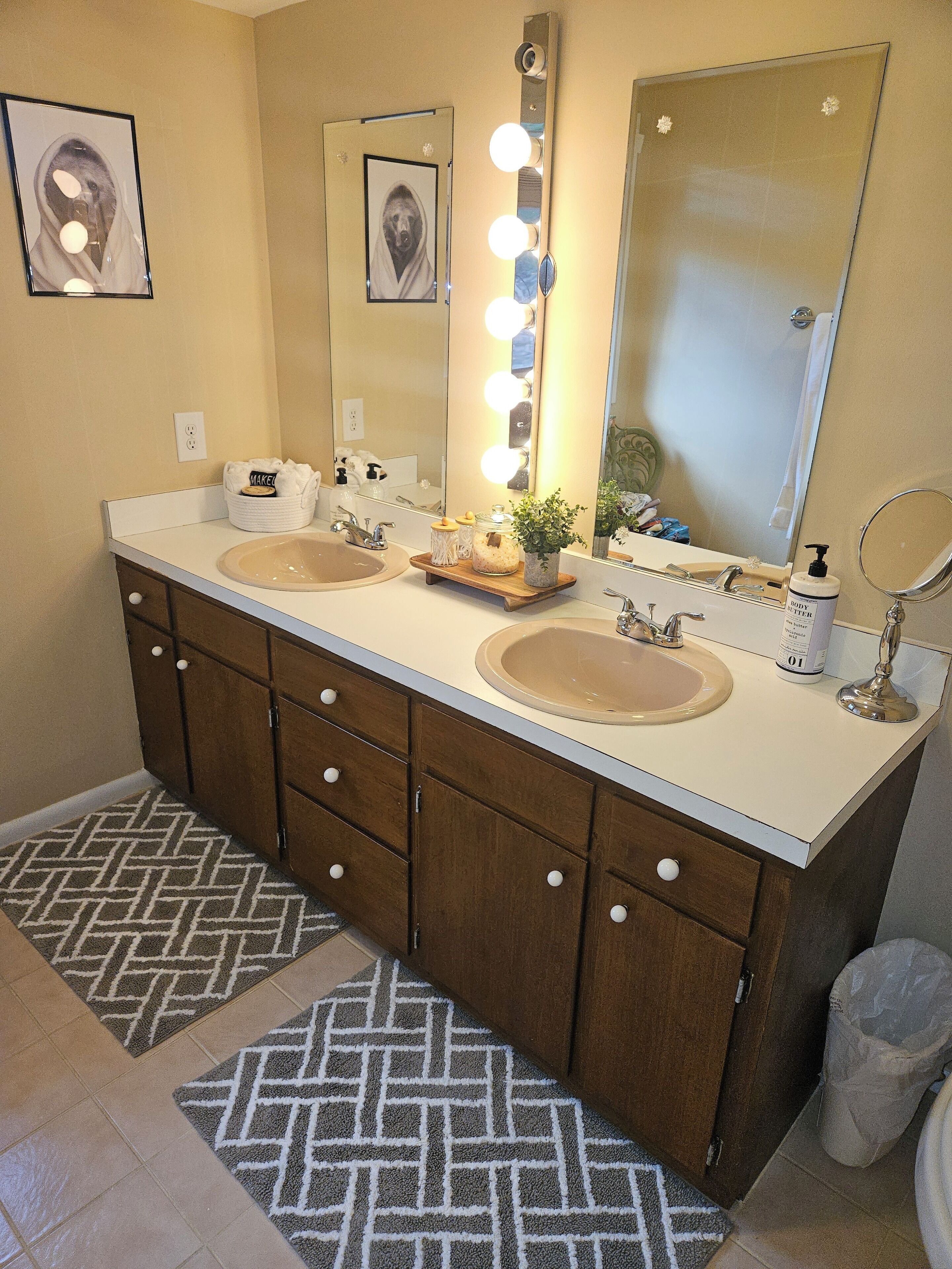 A bathroom with two sinks, vanity mirrors, and a vanity light.