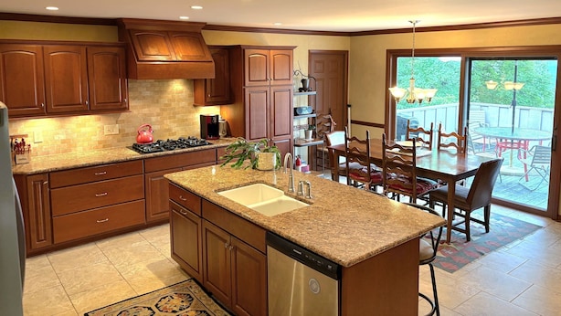 A kitchen with granite countertops, wooden cabinets, a dishwasher, and a dining area with a table and chairs. - Mountain View Chalet in Boone -10 min. to ASU & Downtown; Pet-Friendly (Boone)