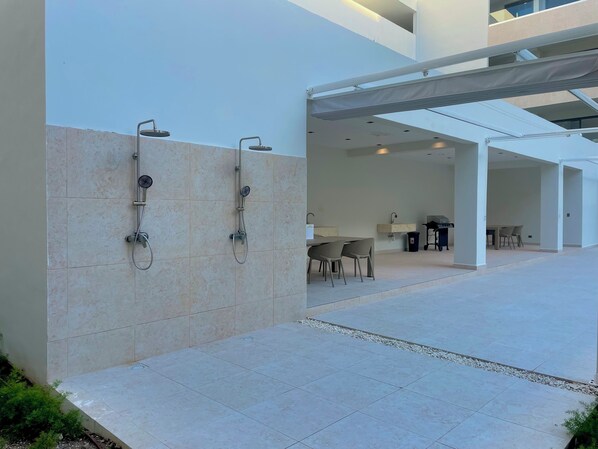 A modern outdoor area with a covered seating area, a small table, and a grill.