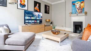Ein modernes Wohnzimmer mit Flachbildfernseher, grauen Sofas, einem Couchtisch und einem Kamin.