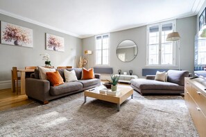 A modern living room with two sofas, a coffee table, and a dining area. - Elegant 3-Bedroom Covent Garden Apartment with Modern Comforts (London)