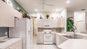Una cocina moderna con armarios blancos, microondas, estufa y pileta.