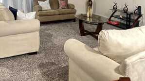 A living room with a sofa, armchairs, a coffee table, a TV, and a painting on the wall. - Tranquil studio in delightful Palm Coast . DBPR License number DWE2801215 (Palm Coast)