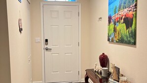 A hallway with a white door, a patterned rug, and a table with decorative items. - Tranquil studio in delightful Palm Coast . DBPR License number DWE2801215 (Palm Coast)