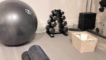 A gym with a large exercise ball, a set of dumbbells, and a foam roller.