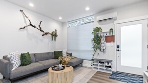Un salon moderne avec un canapé gris, une table basse ronde en bois et une décoration murale en forme de branche.