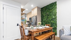 Une cuisine moderne avec des meubles en bois, un réfrigérateur en acier inoxydable et un mur vert.