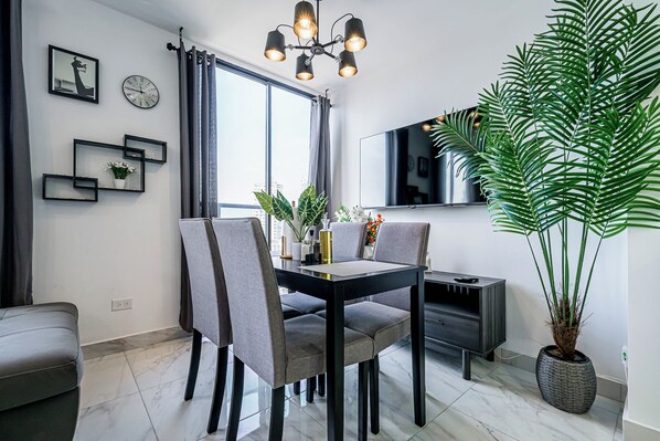 A modern dining area with a black table, grey chairs, and a large potted plant. - The Gray by Wynwood House (Panama City)