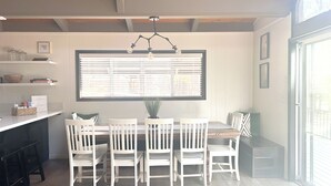A dining area with a table and chairs, a window with blinds, and a ceiling light fixture.