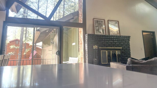 A modern living room with a fireplace, a glass door leading outside, and a wooden ceiling.