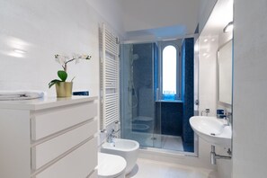 Une salle de bain moderne avec une douche à parois de verre, deux lavabos et des toilettes.