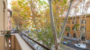 A balcony with a view of a street, trees with autumn leaves, and buildings with graffiti. - Contemporary Flat at Trastevere (Roma)