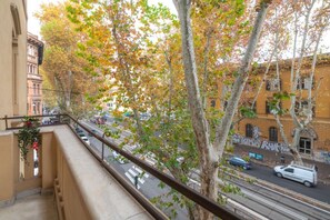 A balcony with a view of a street, trees with autumn leaves, and buildings with graffiti. - Contemporary Flat at Trastevere (Roma)