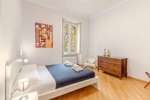 Une chambre à coucher avec un lit, une commode, une chaise et une fenêtre donnant sur un beau paysage.