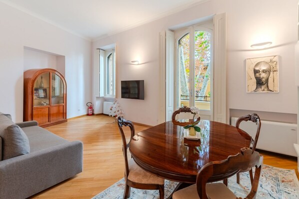 Un coin repas comprenant une table en bois, des chaises, un canapé, un téléviseur et une fenêtre donnant sur un beau paysage.
