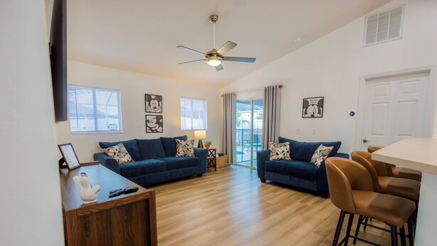 Un salon moderne avec un canapé bleu, une table basse en bois et un ventilateur de plafond.