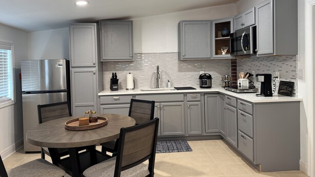 A modern kitchen with grey cabinets, a stainless steel refrigerator, a microwave, and a coffee maker. - La Casita by Amarelys and lazaro (Jacksonville)