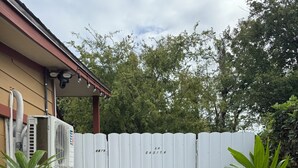 A gated area with a white fence, two potted plants, and an air conditioning unit attached to a building. - La Casita by Amarelys and lazaro (Jacksonville)