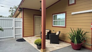 A covered patio area with outdoor furniture, a potted plant, and a white gate. - La Casita by Amarelys and lazaro (Jacksonville)