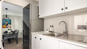 Eine moderne Küche mit weißen Schränken, einer Edelstahl-Spüle und einem eingebauten Kühlschrank.