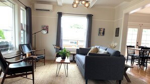 En moderne stue med sofa, stole, et sofabord og en potteplante.