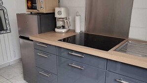 Een moderne keuken met grijze kastjes, een zwart aanrecht, een roestvrijstalen afzuigkap en een koffiezetapparaat.