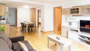 Un salon moderne avec un canapé, une table basse, un téléviseur et une table à manger en bois.