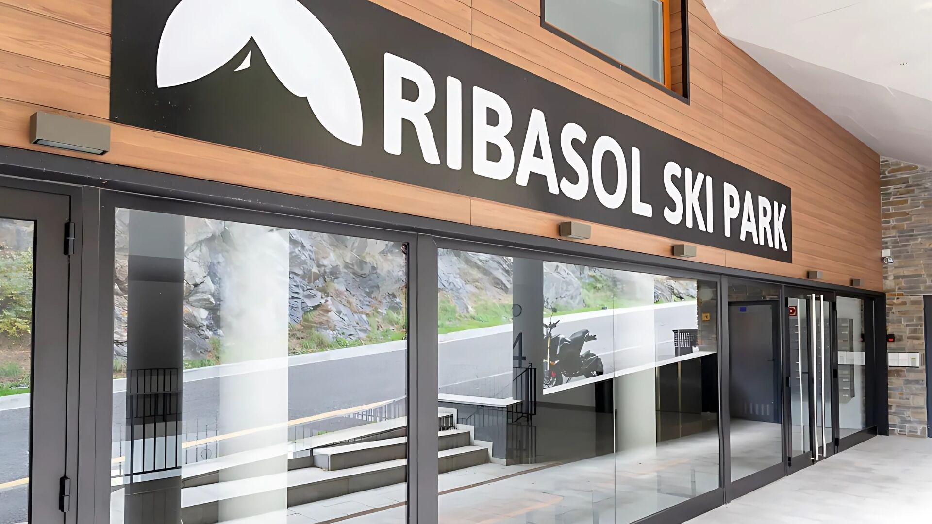 The exterior of Ribasol Ski Park with a wooden facade and large glass doors.