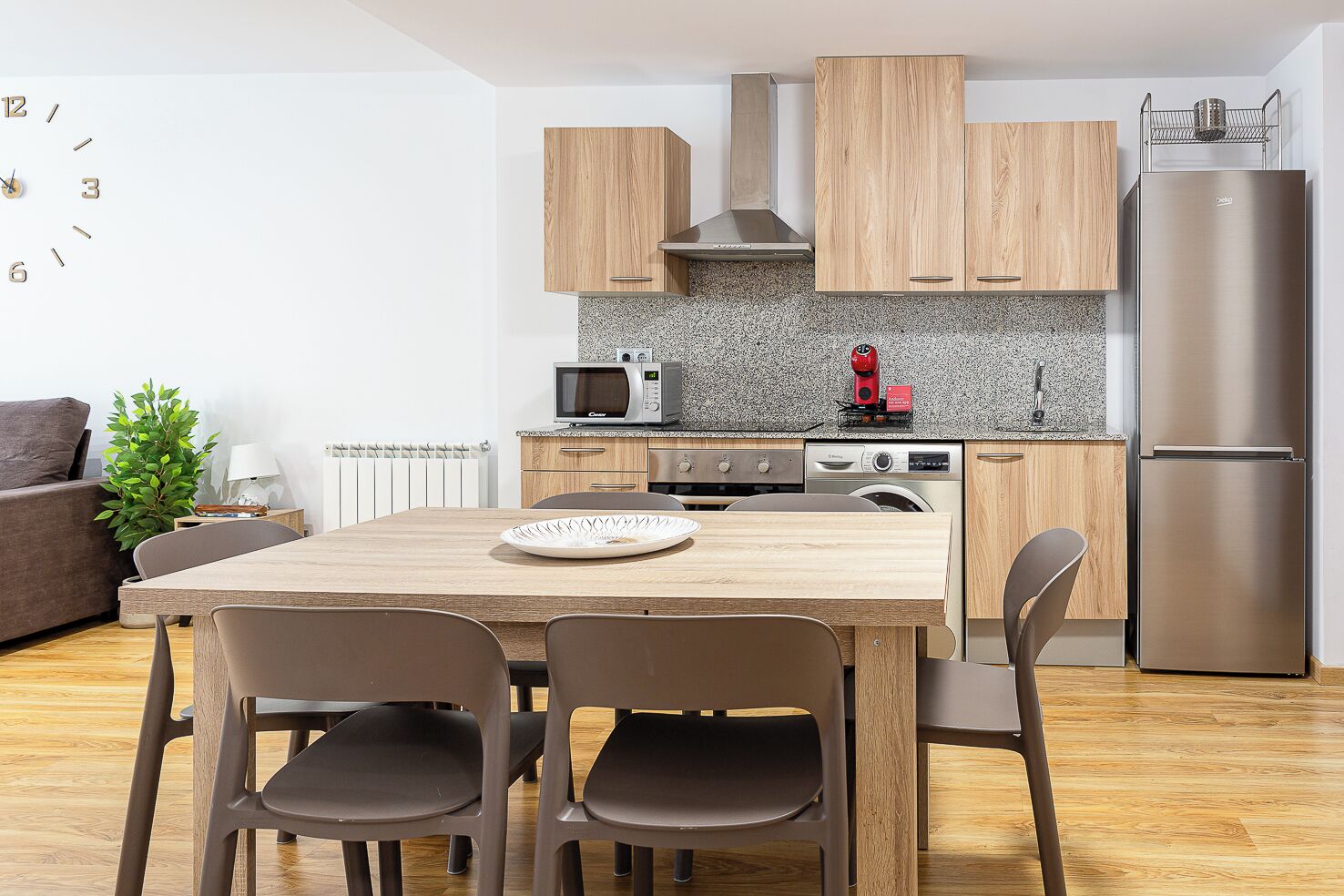 Eine moderne Küche mit Holzschränken, einem Edelstahlkühlschrank, einer Mikrowelle und einer Kaffeemaschine.