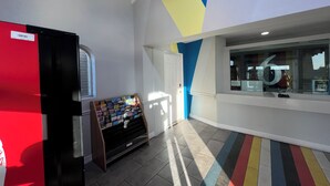 A brightly colored interior with a vending machine, a refrigerator, and a window with a large number. - Studio 6 Phoenix, AZ - Midtown (Phoenix)
