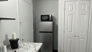 A compact kitchen with a stainless steel refrigerator, a microwave, and a marble countertop. - Studio 6 Phoenix, AZ - Midtown (Phoenix)