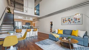 Eine moderne Wohnung mit Essbereich, einem Wohnzimmer mit Sofa und Couchtisch, einer Küche und einer Treppe, die in ein Obergeschoss führt.