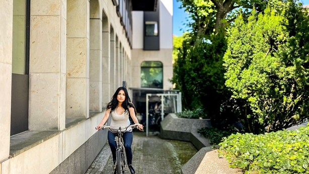 A person riding a bicycle on a cobblestone path between buildings.