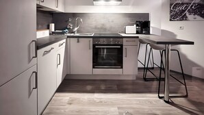 A modern kitchen with a built-in oven, a stainless steel range hood, and a bar stool.
