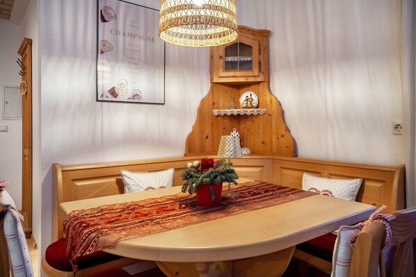 A dining area with a wooden table, chairs, a chandelier, a wall-mounted cabinet, and a framed poster.