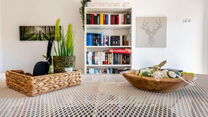 Une pièce comprenant un panier en osier, un bol en bois contenant des œufs, une bibliothèque et un tableau encadré représentant la tête d’un cerf.
