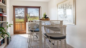 A room with a dining table, white chairs, a bookshelf, and a door leading to a balcony. - Room 'Doppelzimmer 2' with Shared Terrace, Shared Garden and Wi-Fi (Dielheim)