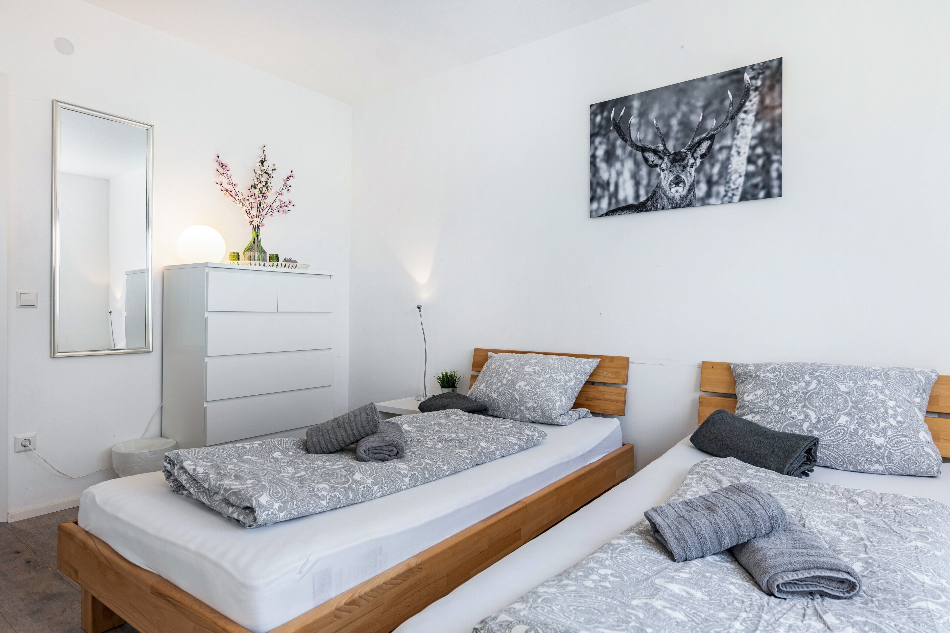 Ein Schlafzimmer mit zwei Betten, einem Schminktisch, einem Spiegel und einem Wandbild.