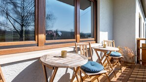 A patio with wooden tables and chairs, large windows, and a view of trees and hills. - Room 'Einzelzimmer' with Shared Terrace, Shared Garden and Wi-Fi (Dielheim)