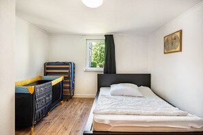 Une pièce avec un lit, une fenêtre avec des rideaux, une petite table et une chaise.