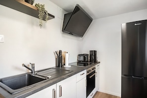 A modern kitchen with a stainless steel sink, a black refrigerator, and a built-in oven.