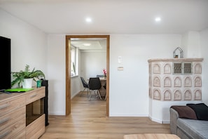 Una sala de estar moderna con un mueble de madera, un televisor y un área de comedor al fondo.