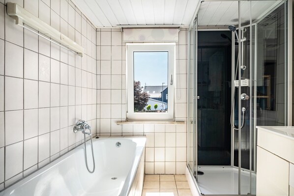 A modern bathroom with a bathtub, a shower enclosure, and a window with a view of the outside.