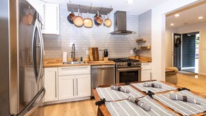 Una cucina moderna con mobili bianchi, elettrodomestici in acciaio inossidabile e un tavolo da pranzo in legno apparecchiato con sottopiatti a righe.