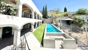 A pool with a clear blue water feature, surrounded by a well-maintained lawn and a white building with multiple arches. - Studio With Salt Water Pool (Chapala)